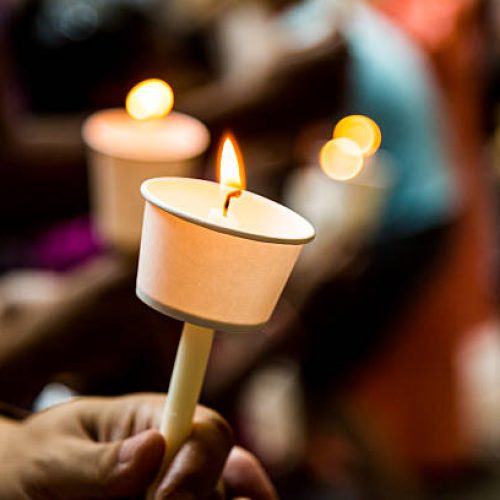 Closeup of people holding candle vigil in darkness expressing and seeking hope Closeup of people holding candle vigil in darkness expressing and seeking hope