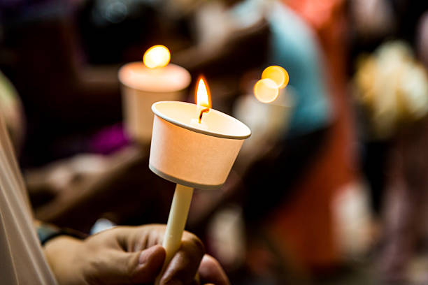 Closeup of people holding candle vigil in darkness expressing and seeking hope Closeup of people holding candle vigil in darkness expressing and seeking hope